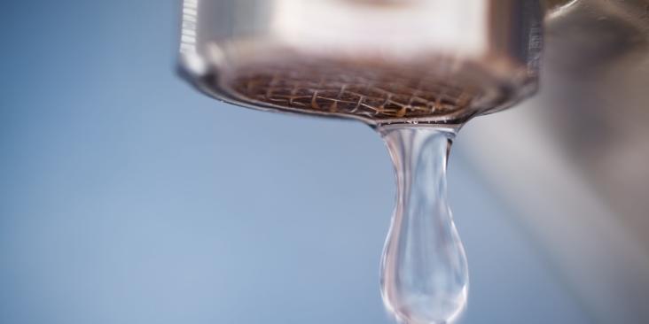 A drop of water coming out of a faucet.