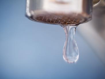 A drop of water coming out of a faucet.